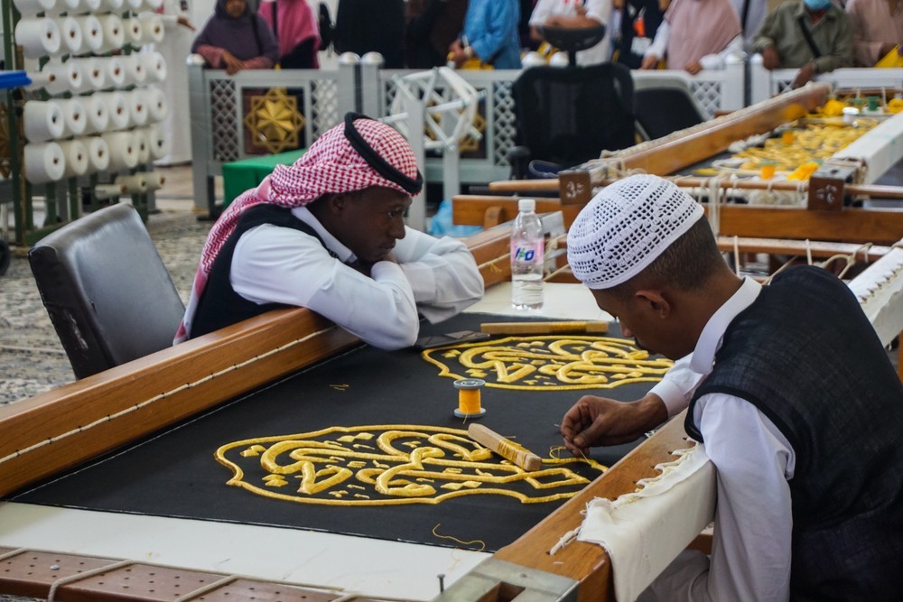 Workers crafting the Kaaba’s Kiswah at the King Abdulaziz Factory in Makkah, weaving black silk with gold Quranic calligraphy